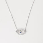 The Blue Center Evil Eye Necklace is crafted from fine silver, featuring a delicate eye design with a shimmering blue center surrounded by bright zircon stones.
