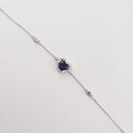 The Blue Heart Bracelet is a delicate fine silver piece featuring a stunning heart-shaped blue zircon stone, framed with sparkling clear zircons.