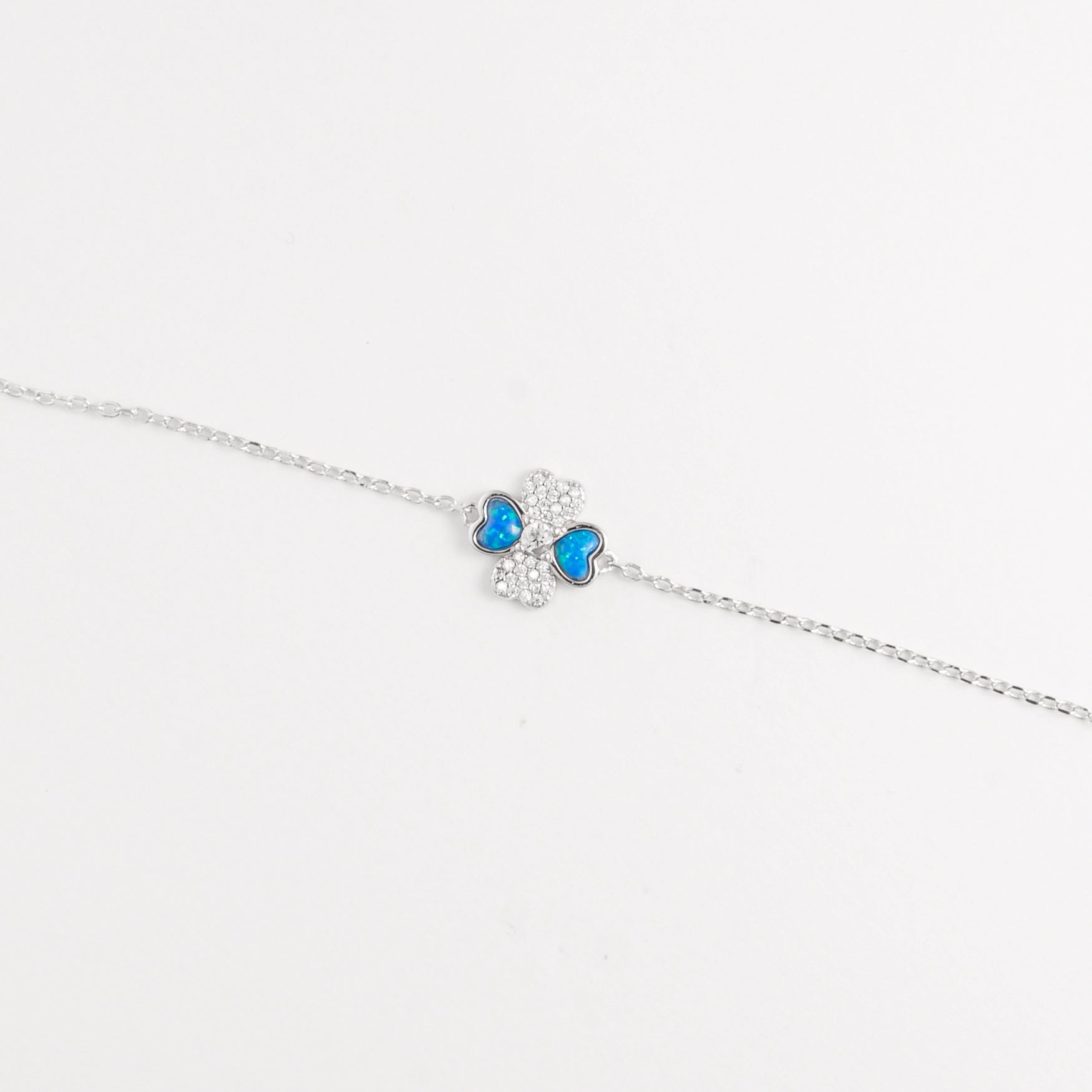 The Blue Heart Clover Bracelet is a delicate piece made from fine silver, adorned with shimmering zircon stones. Its charming four-leaf clover design features vibrant blue heart-shaped accents, symbolizing luck and love.