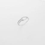 The Crystal Crossover Ring showcases a sleek silver band with a graceful twist. One side sparkles with baguette-cut zircon stones, while the other is set with delicate crystals for a soft, radiant finish.