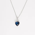The Deep Blue Heart Necklace is a timeless piece crafted from fine silver, featuring a striking heart-shaped deep blue stone that captures the eye with its rich color and graceful cut.