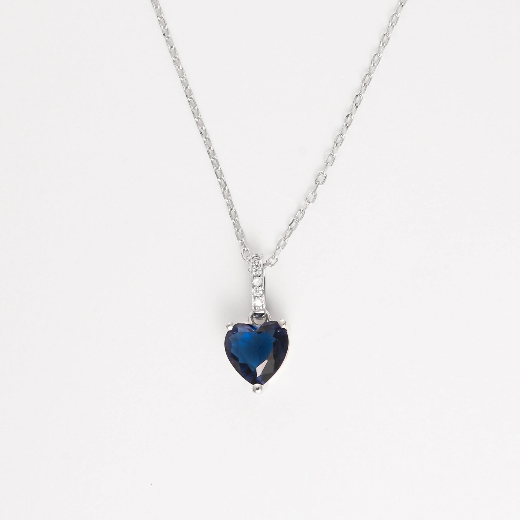 The Deep Blue Heart Necklace is a timeless piece crafted from fine silver, featuring a striking heart-shaped deep blue stone that captures the eye with its rich color and graceful cut.