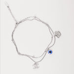 Step into summer with good vibes and playful energy. The Evil Eye Charm Anklet is crafted from fine silver and features a double-layer chain, delicate beaded details, and three bold charms a shining evil eye, a modern face line art charm, and a sleek monogram accent.