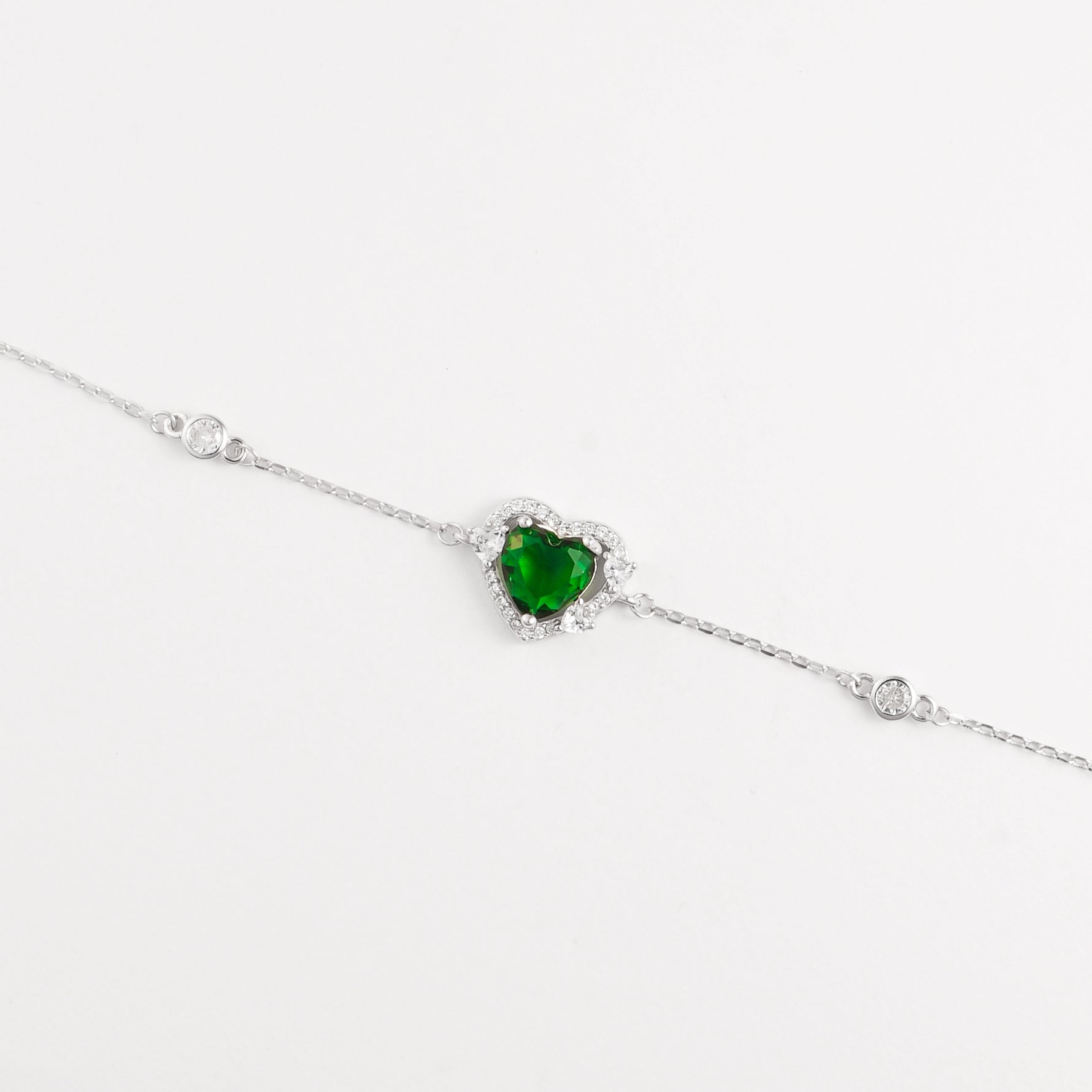 The Green Heart Bracelet is a delicate fine silver piece featuring a stunning heart-shaped green zircon stone, framed with sparkling clear zircons.