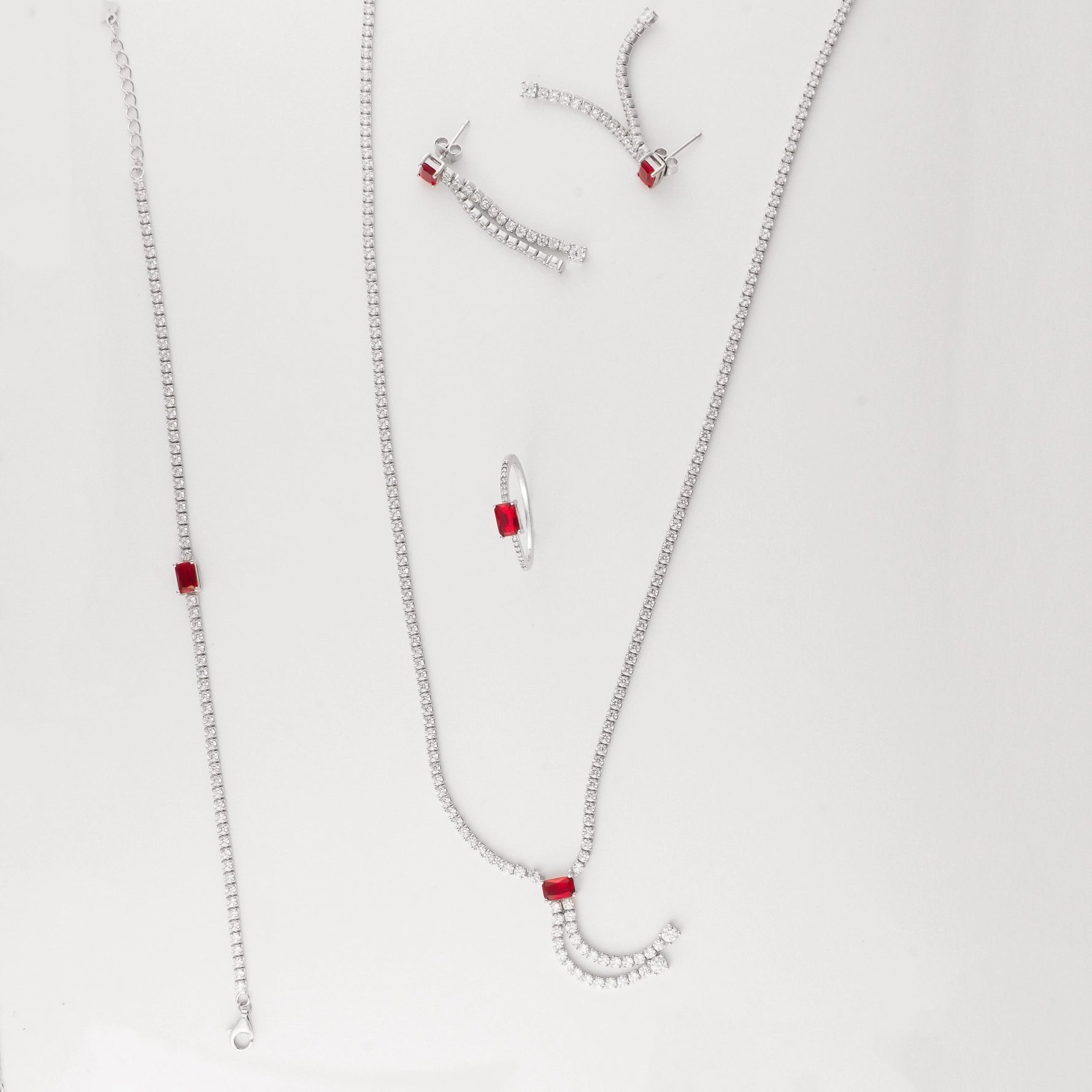 This set features a graceful necklace with cascading zircon stones and a bold red crystal center, paired perfectly with a matching bracelet, sleek ring, and dramatic drop earrings. The contrast of red and white stones adds a modern twist to classic sparkle, perfect for evening wear.