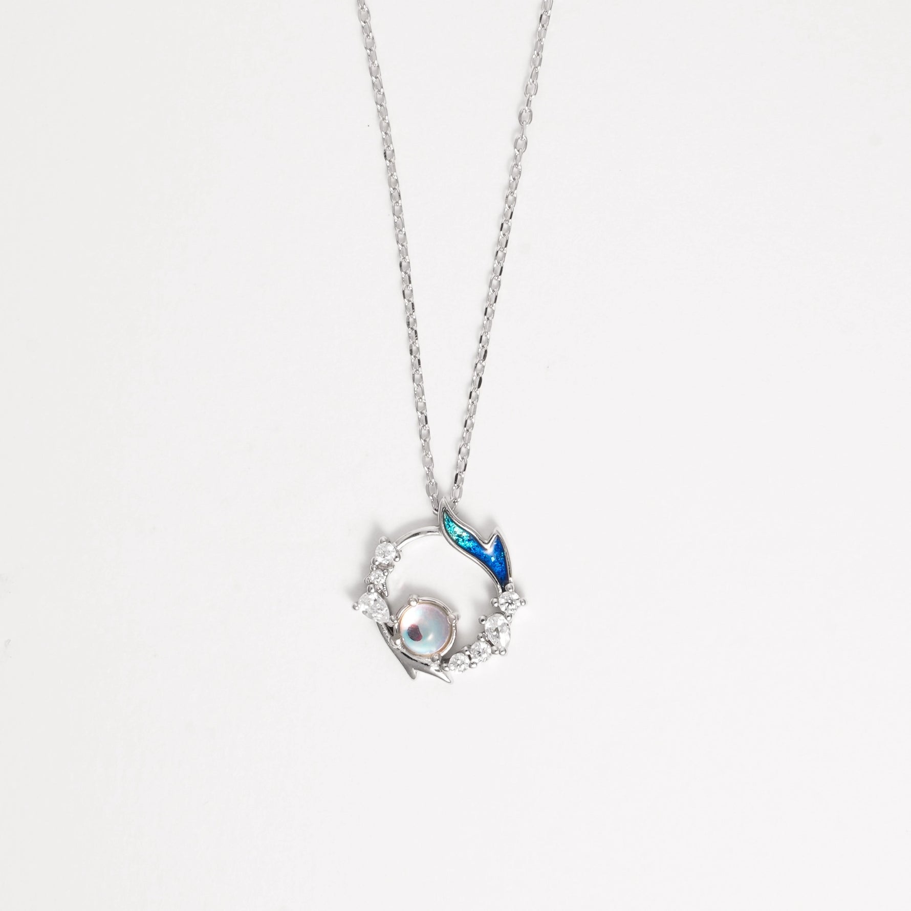 The Mermaid Pearl Necklace captures the enchanting beauty of the sea. Crafted from fine silver and sparkling zircon stones, it features a delicate circular design with a shimmering pearl at its heart and a touch of blue enamel that evokes ocean waves.