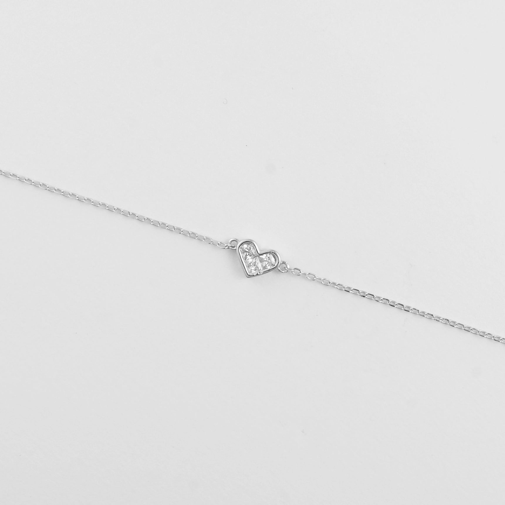 The Mini Heart Bracelet features a dainty heart-shaped charm delicately filled with clear zircon stones.
