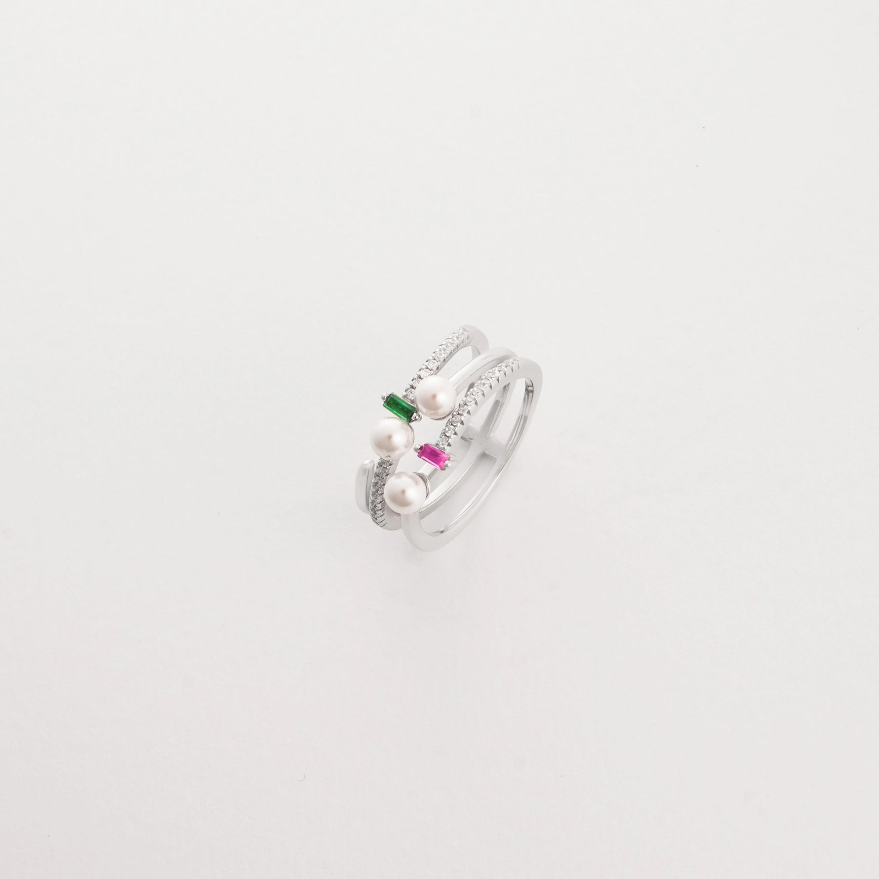 The Pearl Spark ring features a sleek double band adorned with soft pearls, bright pink and green stones, and sparkling zircon details.