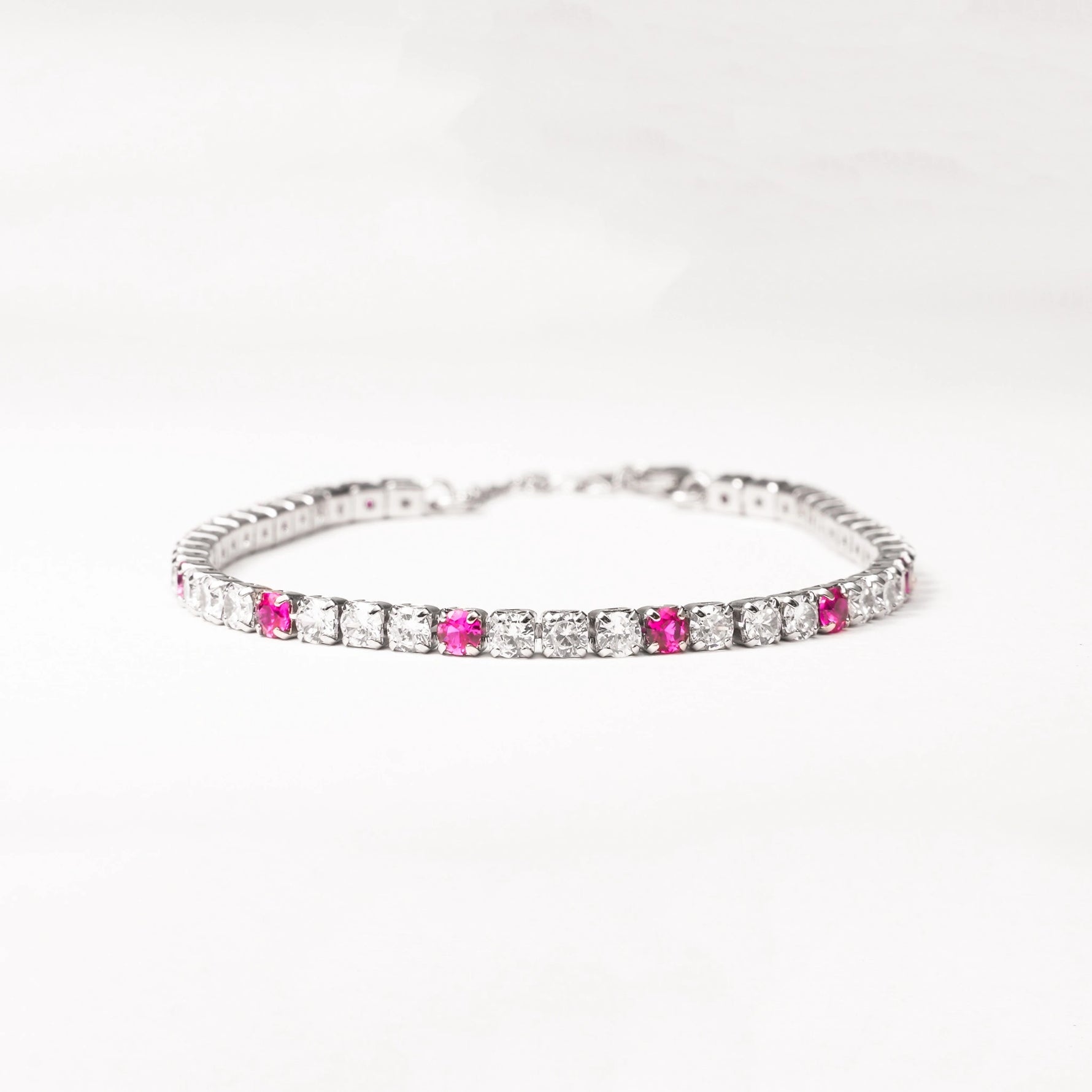 Add a pop of color with the Pink Accent Tennis Bracelet, crafted from fine silver and sparkling zircon stones. This elegant bracelet features shimmering clear stones accented by vibrant pink zircons, making it a perfect blend of classic and playful style.