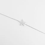 The Sparkling Star Bracelet features a delicate silver chain with a radiant star-shaped charm at its center.