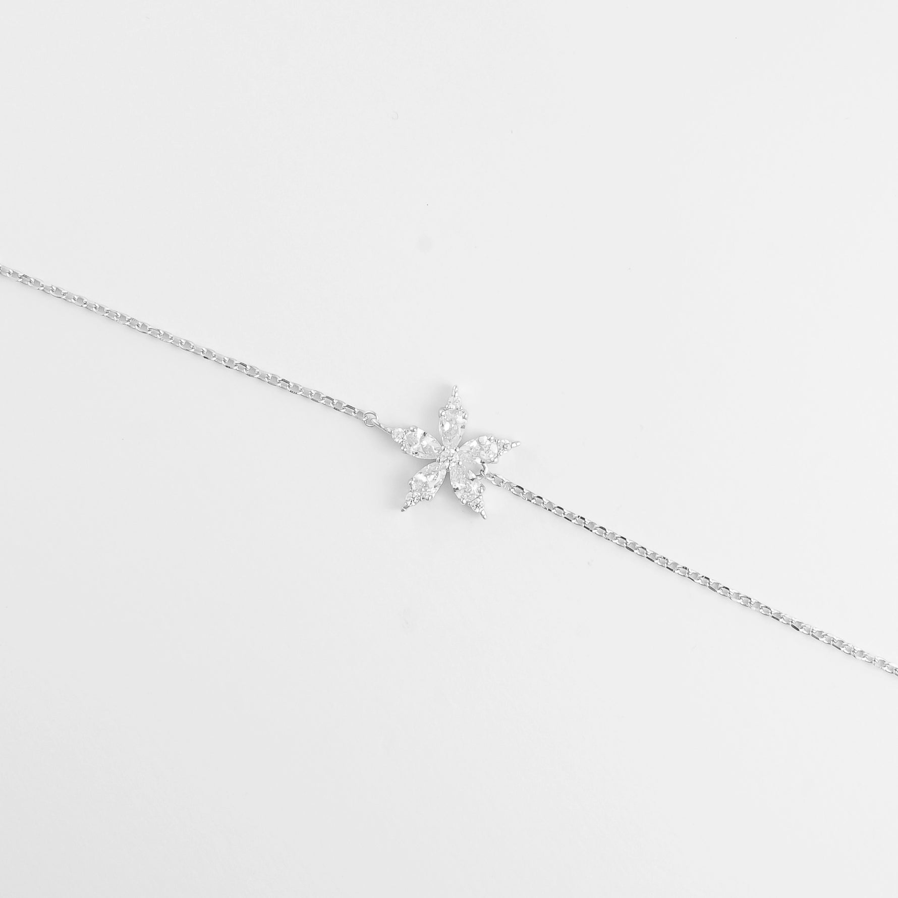 The Sparkling Star Bracelet features a delicate silver chain with a radiant star-shaped charm at its center.