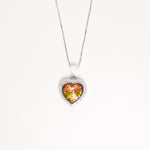The Sunset Heart Necklace captures the magic of a glowing sky. Set in silver, its heart-shaped crystal shifts from light pink to golden yellow and green, reflecting the beauty of a sunset.