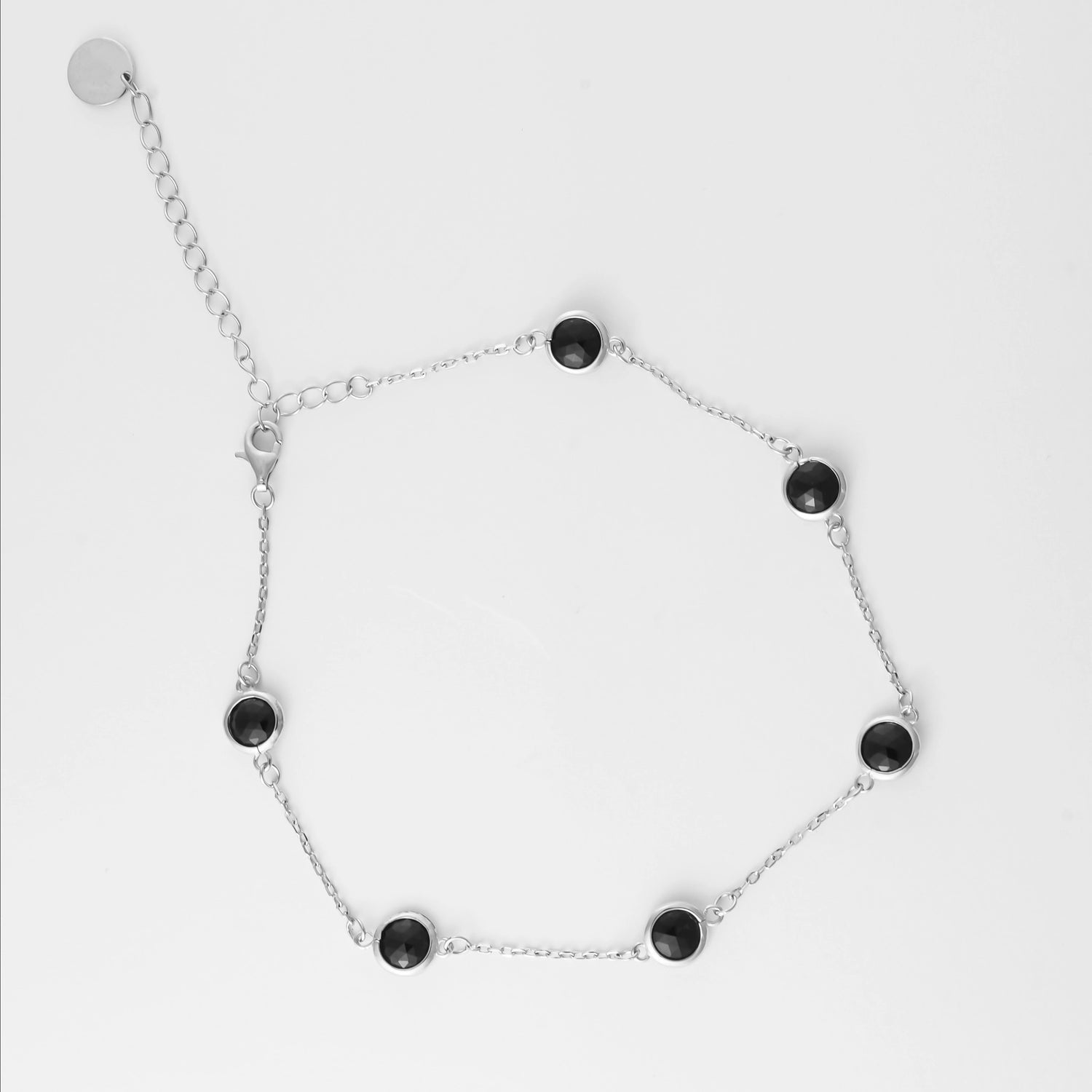 Sleek, stylish, and made to shine under the sun. The Black Gem Anklet features a fine silver chain adorned with glossy black round gems that catch the light with every step. 