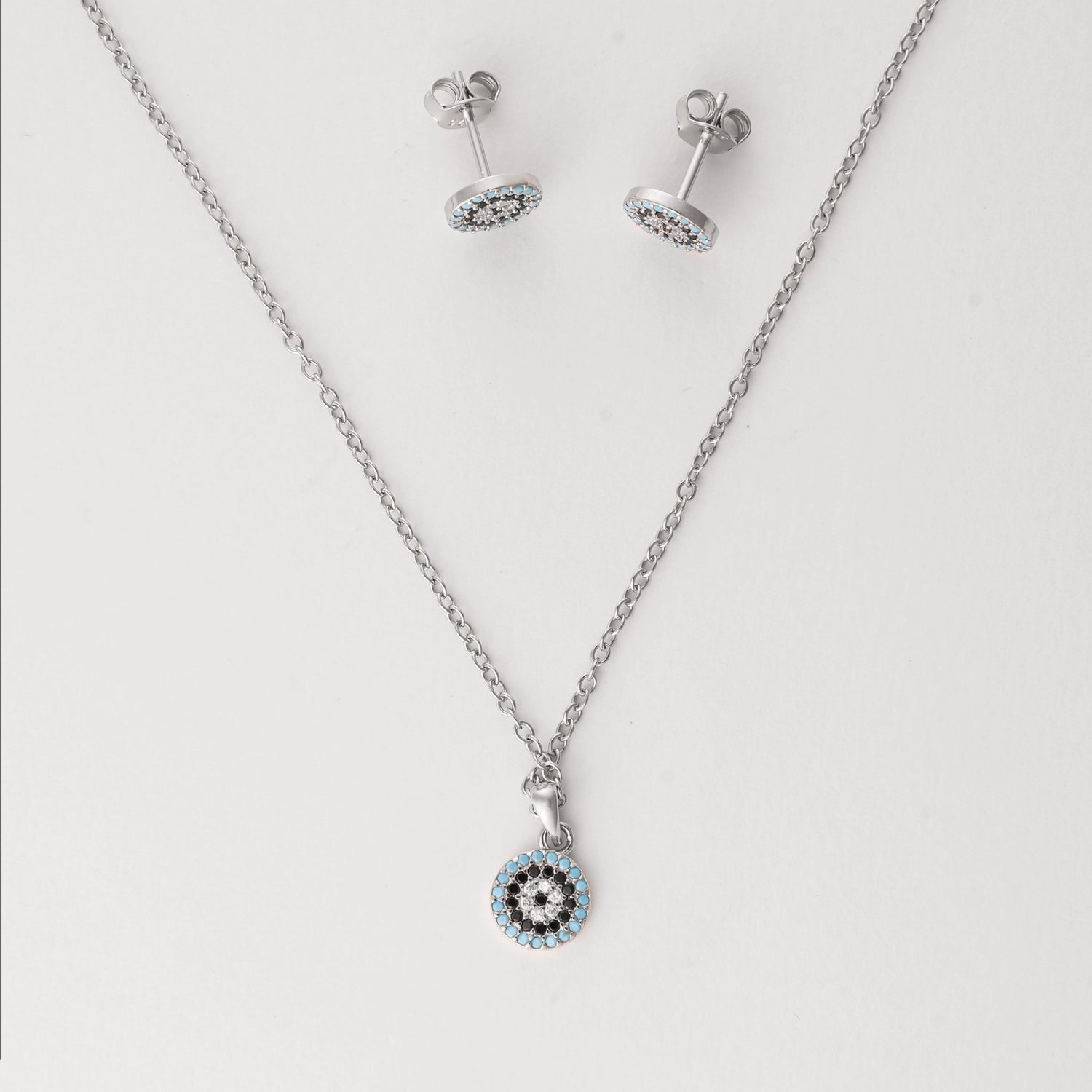 Elegant with a hint of mystique, the Blue Evil Eye Half Set brings protection in one refined design. Crafted from fine silver and accented with sparkling zircon stones, the round pendant and matching earrings feature the iconic evil eye symbol in tones of sky blue, black, and white. 