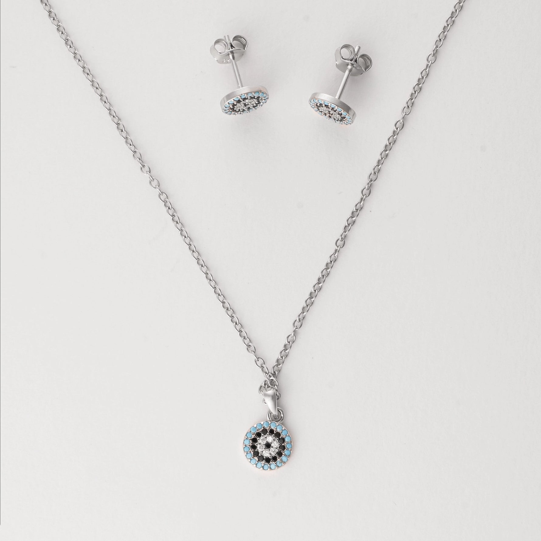 Elegant with a hint of mystique, the Blue Evil Eye Half Set brings protection in one refined design. Crafted from fine silver and accented with sparkling zircon stones, the round pendant and matching earrings feature the iconic evil eye symbol in tones of sky blue, black, and white. 