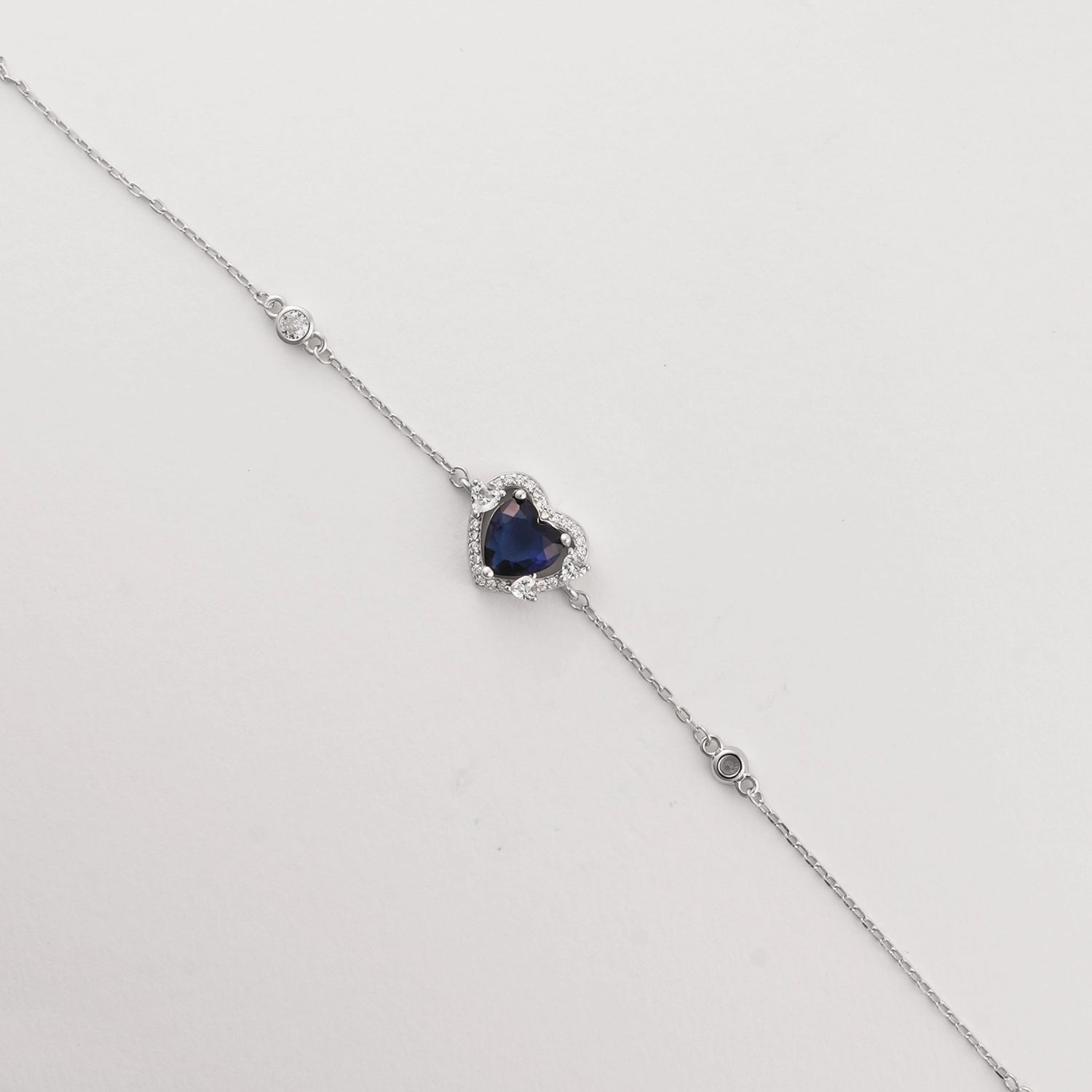 The Blue Heart Bracelet is a delicate fine silver piece featuring a stunning heart-shaped blue zircon stone, framed with sparkling clear zircons.
