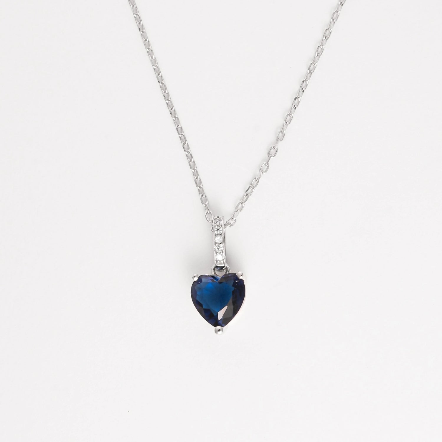 The Deep Blue Heart Necklace is a timeless piece crafted from fine silver, featuring a striking heart-shaped deep blue stone that captures the eye with its rich color and graceful cut.