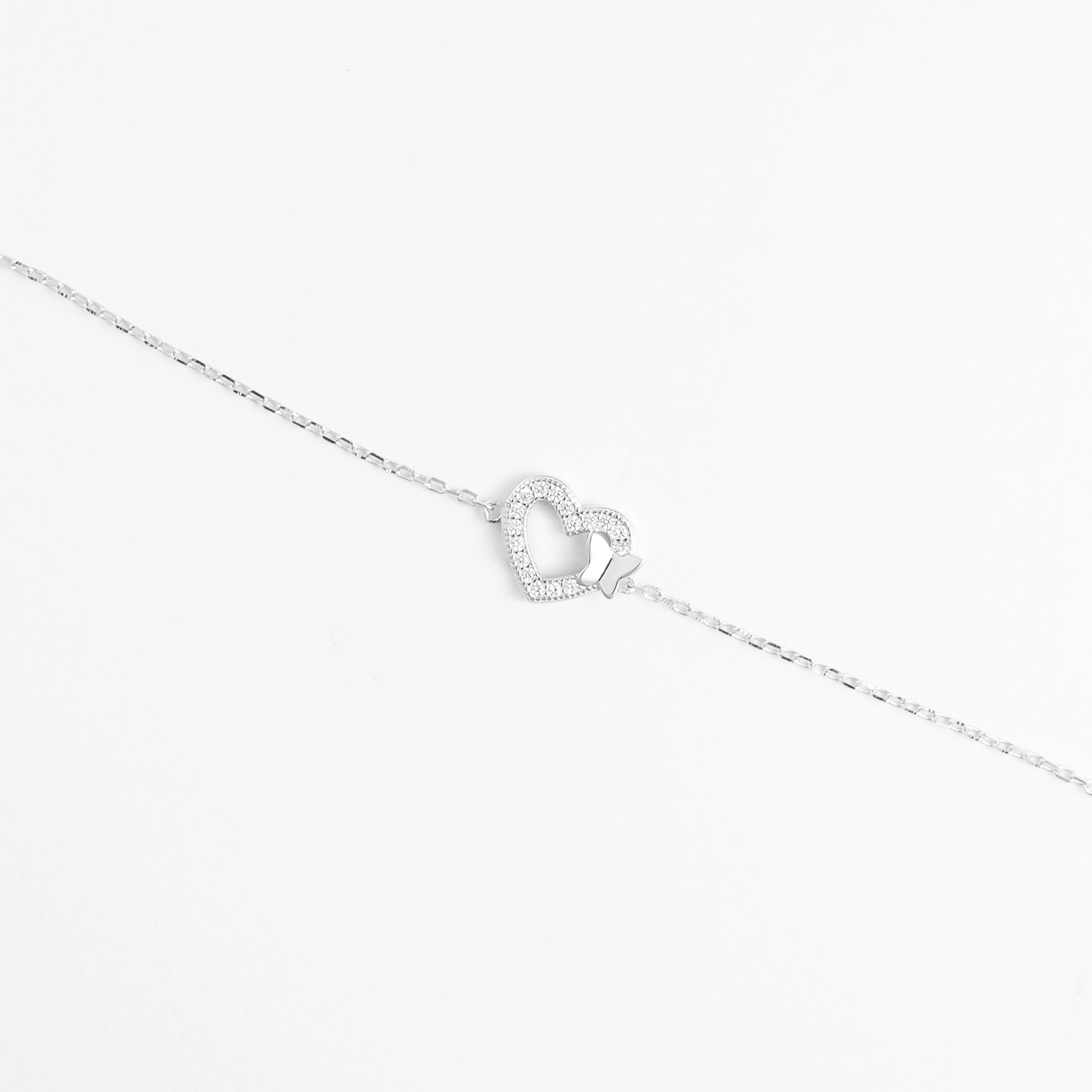 The Butterfly Heart Bracelet features a graceful heart outline adorned with sparkling zircon stones, gently touched by a tiny butterfly charm.