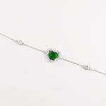 The Green Heart Bracelet is a delicate fine silver piece featuring a stunning heart-shaped green zircon stone, framed with sparkling clear zircons. 