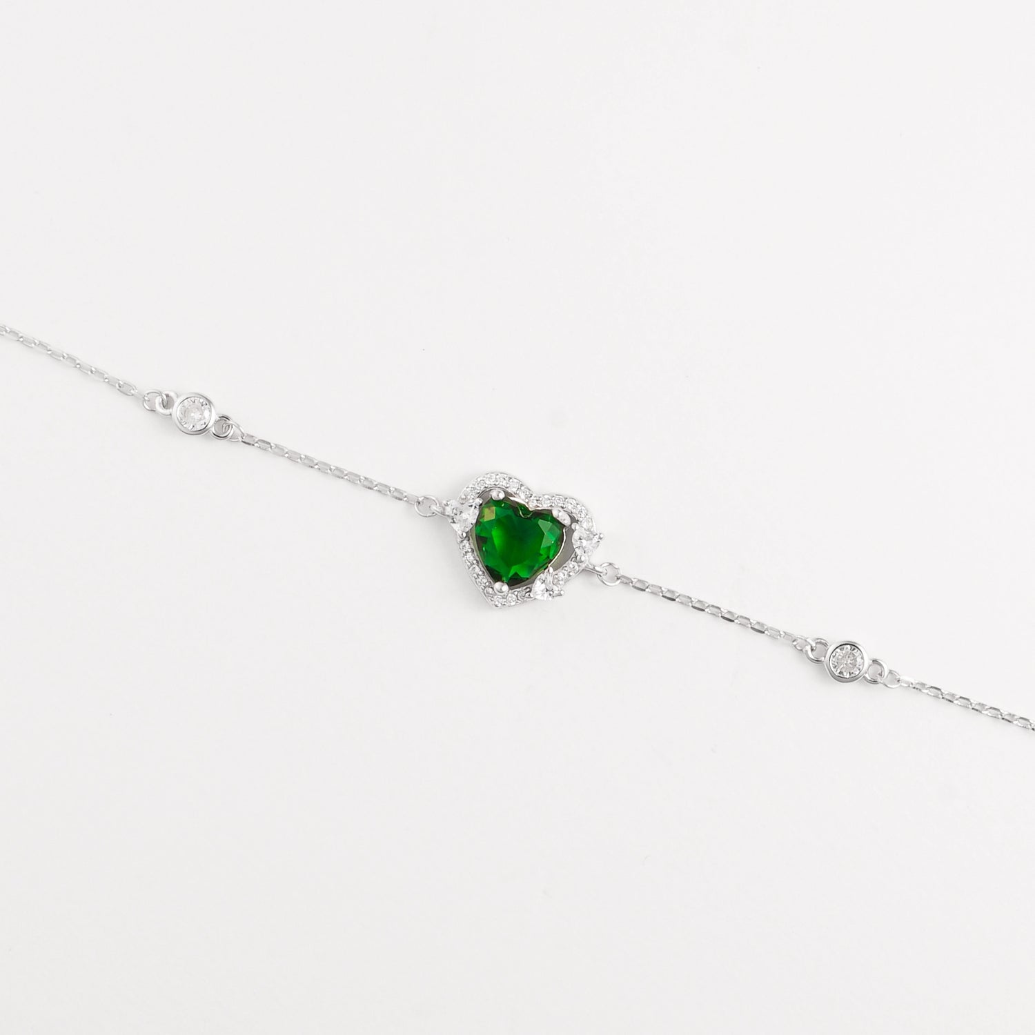 The Green Heart Bracelet is a delicate fine silver piece featuring a stunning heart-shaped green zircon stone, framed with sparkling clear zircons. 