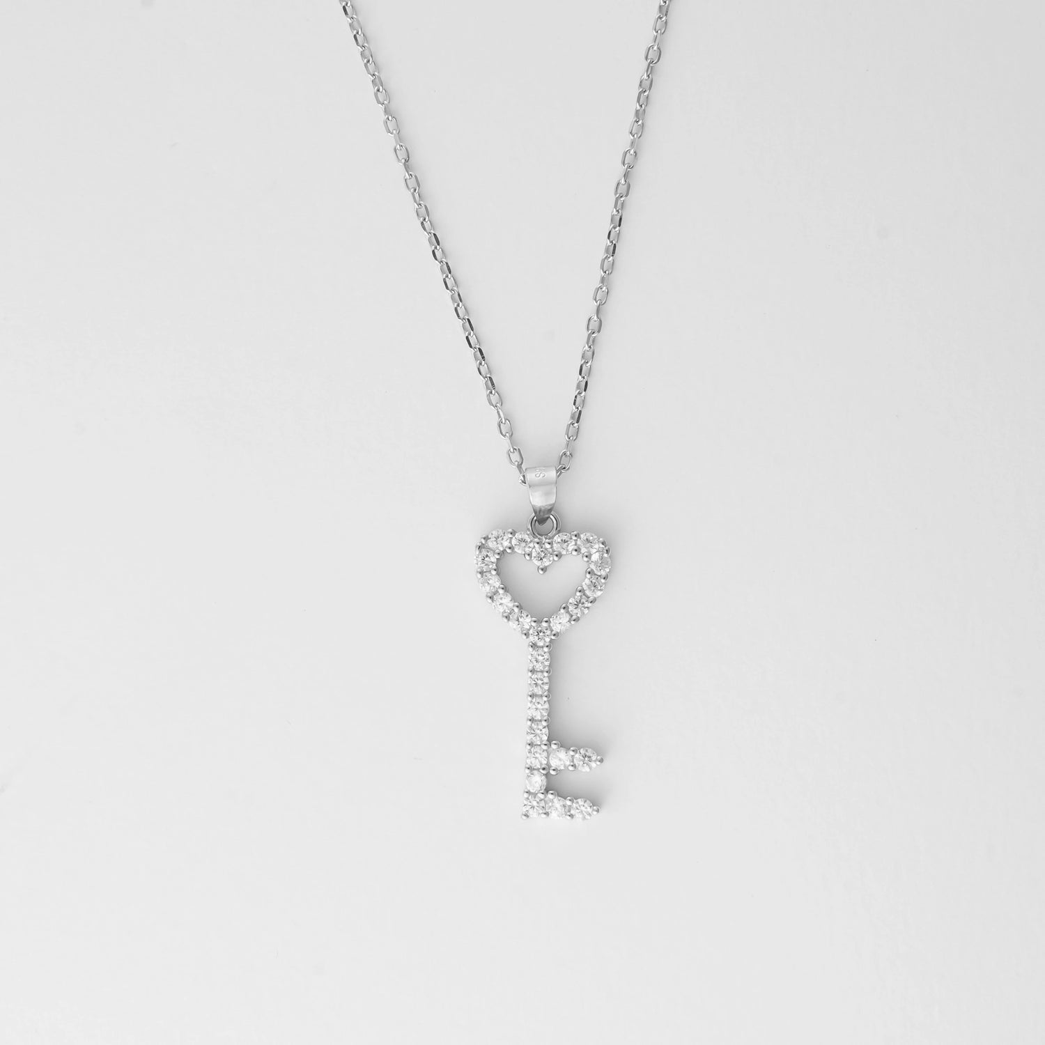 The Heart Key Necklace is a delicate symbol of love and elegance. Crafted from fine silver and sparkling zircon stones, this necklace features a key pendant shaped with a charming heart at its top. 