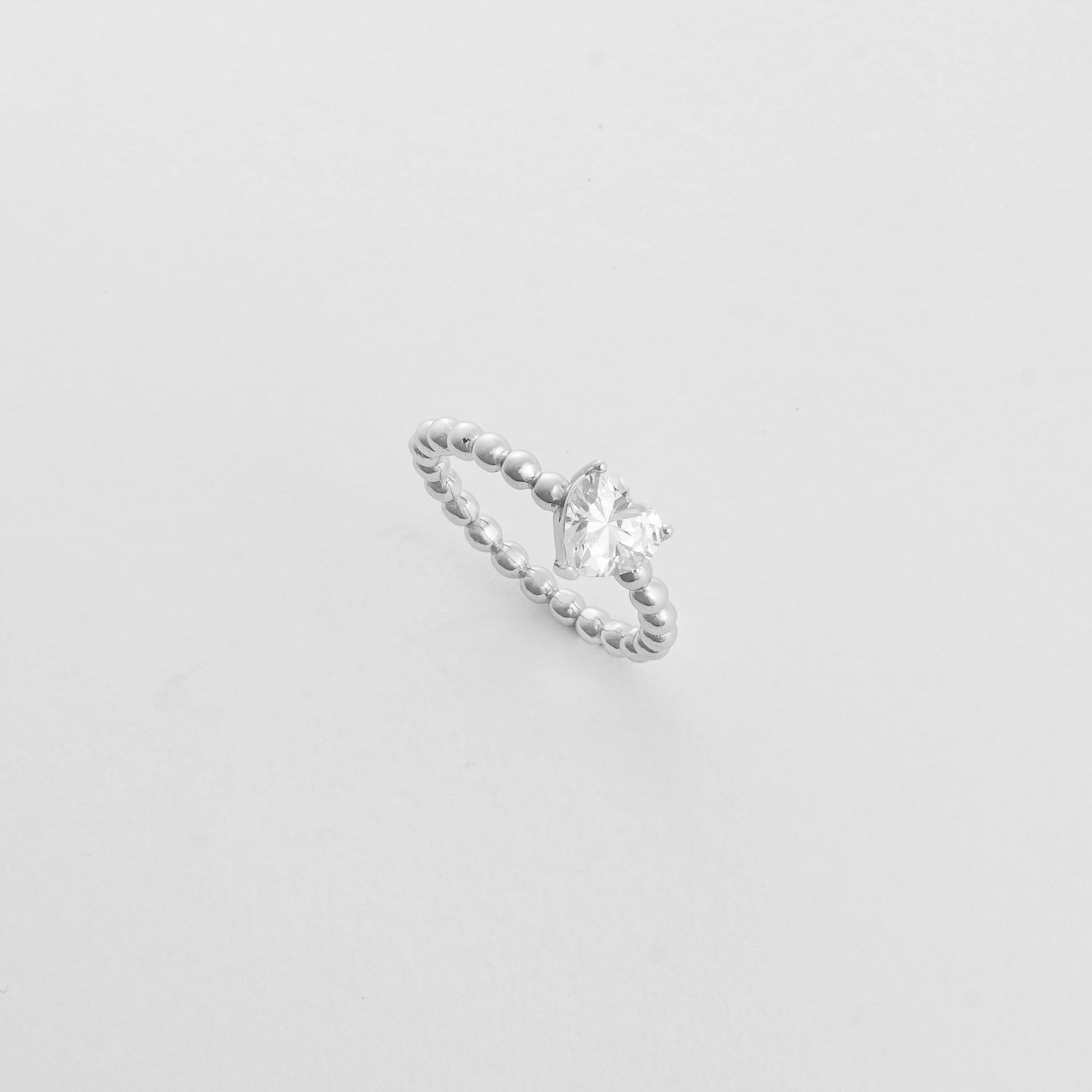 The Heart Solitaire ring features a radiant heart-cut stone resting on a silver bead-style band.