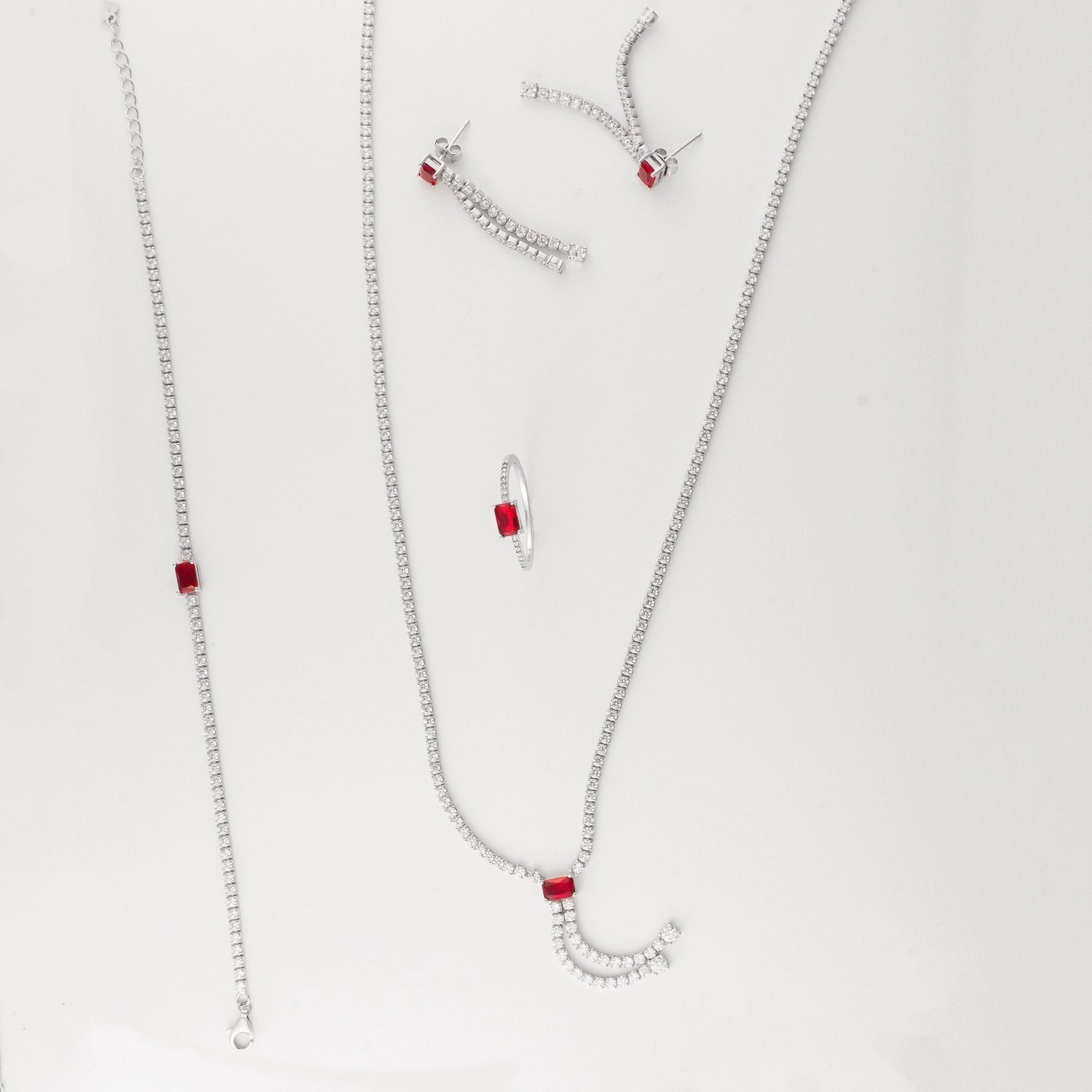  This set features a graceful necklace with cascading zircon stones and a bold red crystal center, paired perfectly with a matching bracelet, sleek ring, and dramatic drop earrings. The contrast of red and white stones adds a modern twist to classic sparkle, perfect for evening wear. 