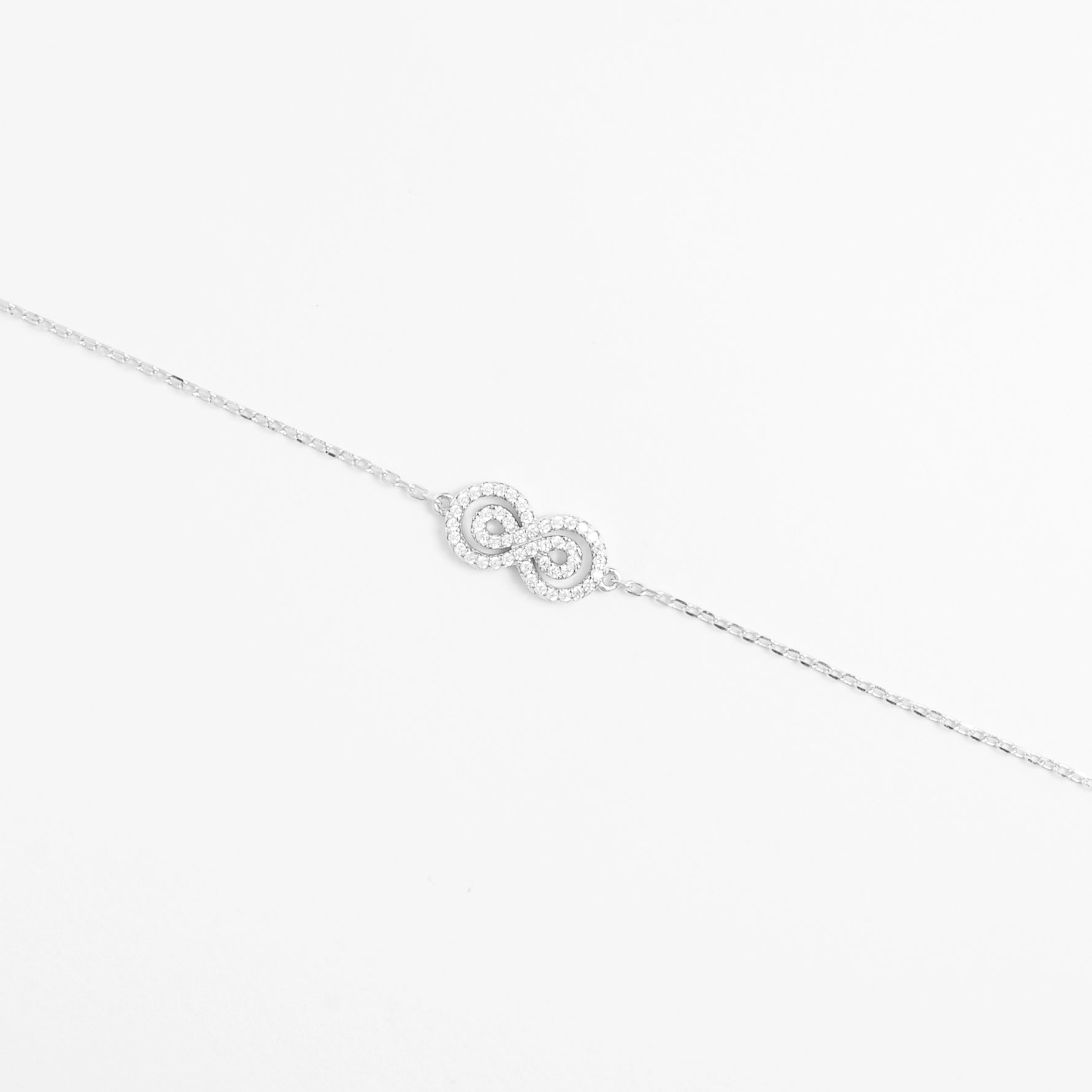 The Infinity Bracelet is a timeless fine silver piece designed with a sparkling infinity symbol encrusted with delicate zircon stones.