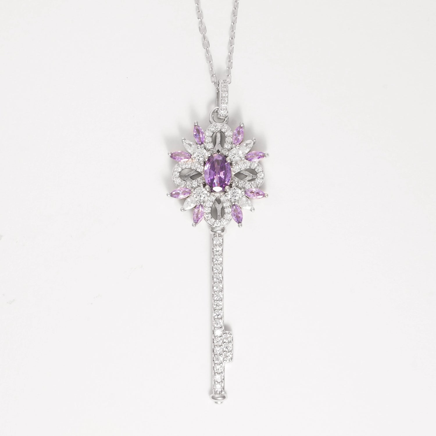 The Key to Elegance Necklace is a beautifully crafted piece in fine silver, featuring a delicate key pendant adorned with shimmering zircon stones and sparkling purple crystals.