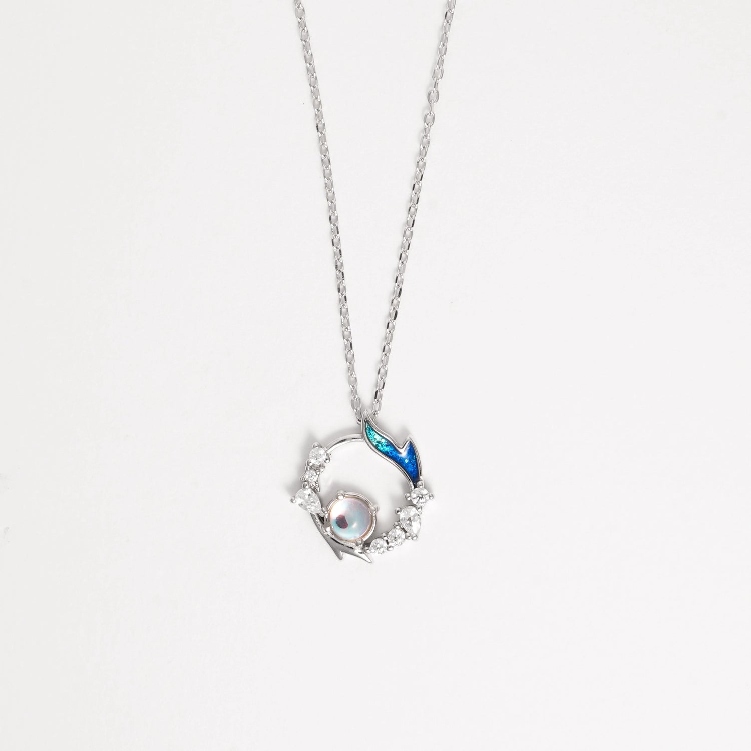The Mermaid Pearl Necklace captures the enchanting beauty of the sea. Crafted from fine silver and sparkling zircon stones, it features a delicate circular design with a shimmering pearl at its heart and a touch of blue enamel that evokes ocean waves.