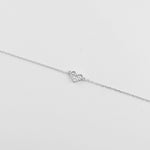 The Mini Heart Bracelet features a dainty heart-shaped charm delicately filled with clear zircon stones.