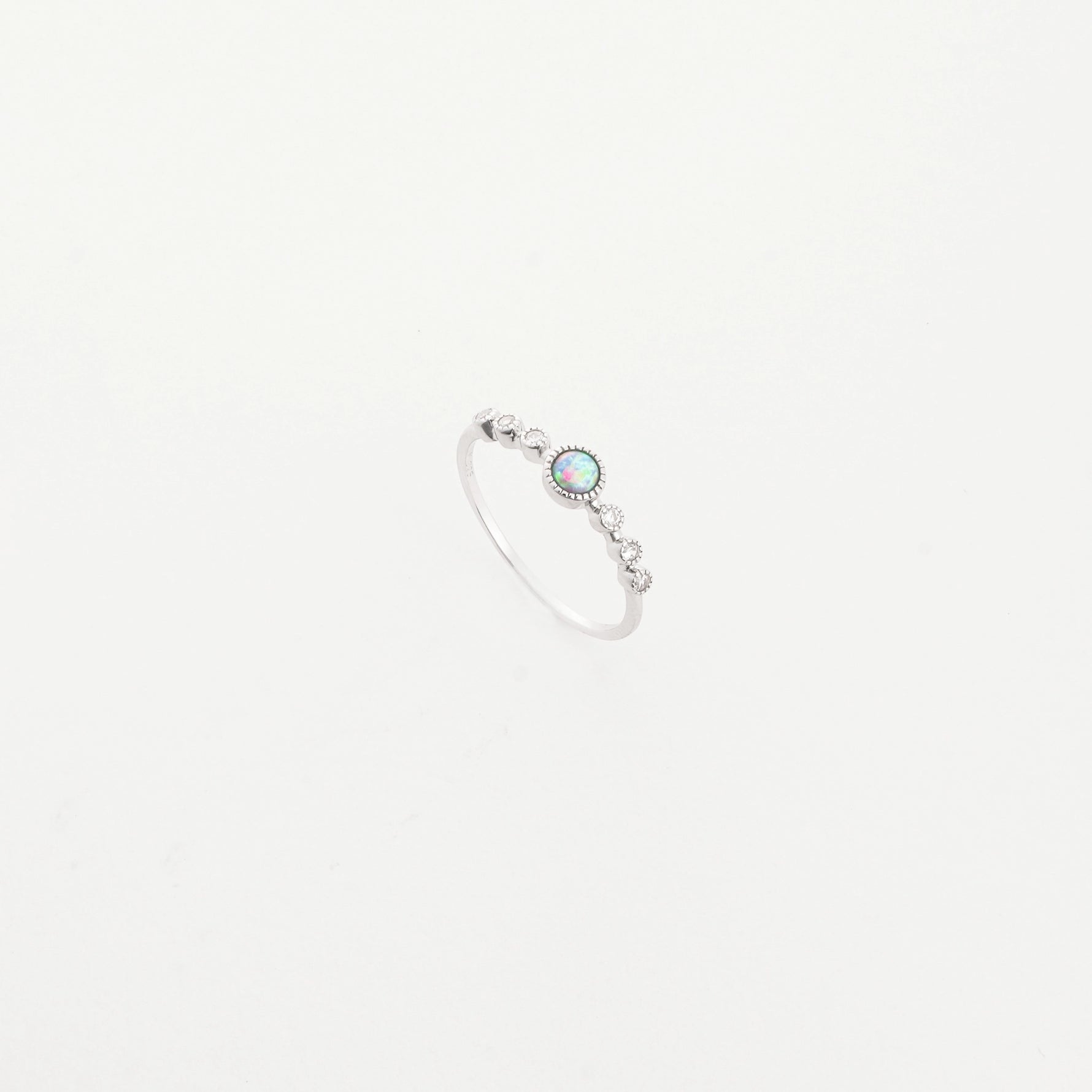 The Opal Accent Ring is a delicate fine silver piece that sparkles with a beautiful opal stone at its center.