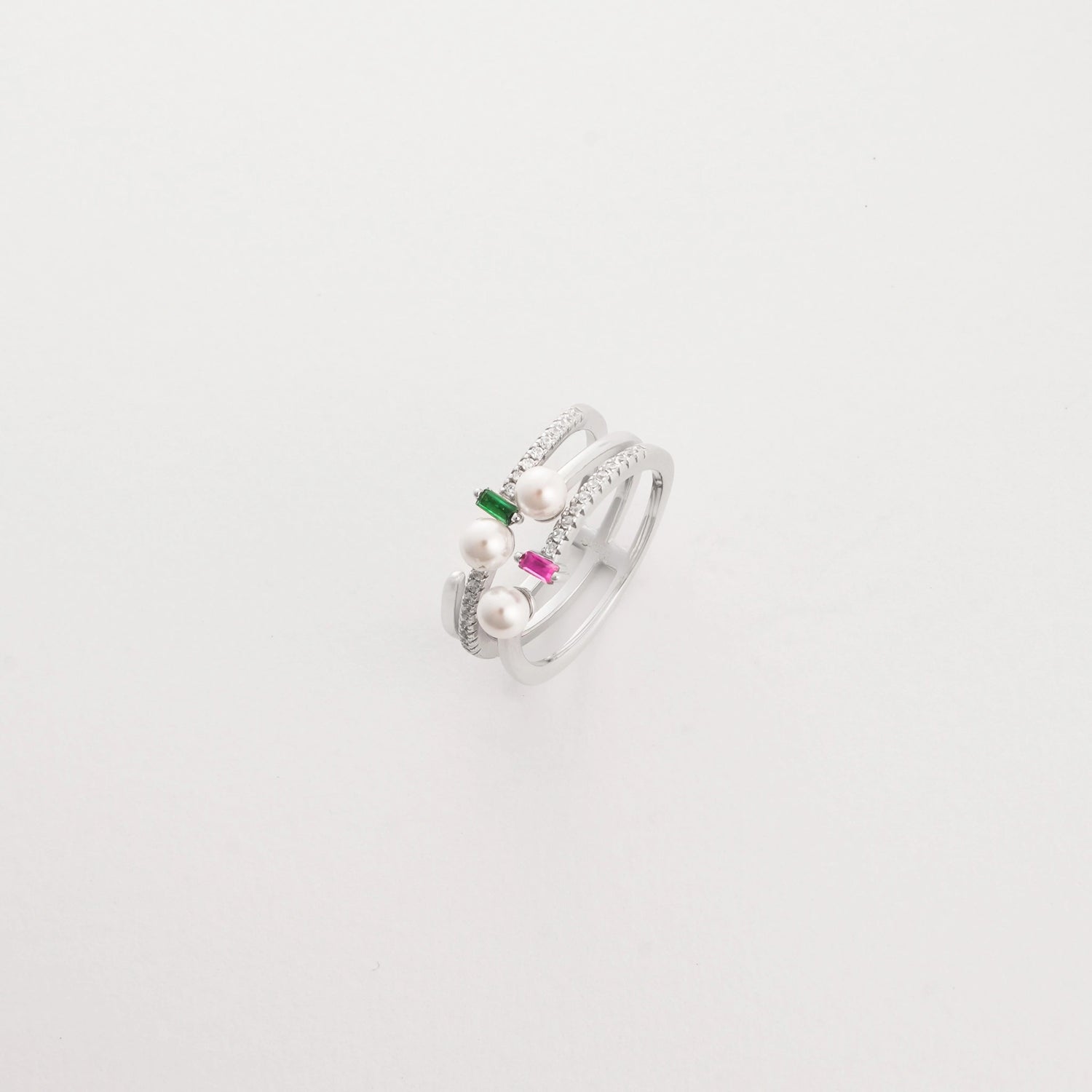 The Pearl Spark ring features a sleek double band adorned with soft pearls, bright pink and green stones, and sparkling zircon details.