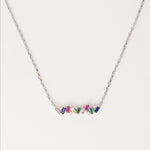 The Rainbow Gem Bar Necklace is a vibrant and elegant piece made from fine silver, featuring a row of dazzling zircon stones in a spectrum of colors.