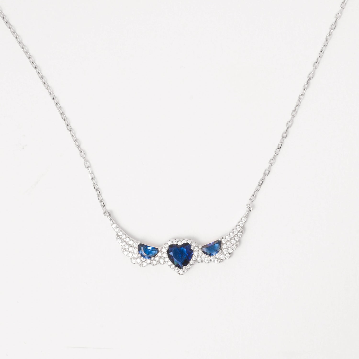 A symbol of love and elegance, the Sapphire Heart Trio Wing Necklace features three dazzling blue heart crystals embraced by wing-like curves of shimmering zircon stones. Set in pure silver, its winged design brings a graceful lift to any look.