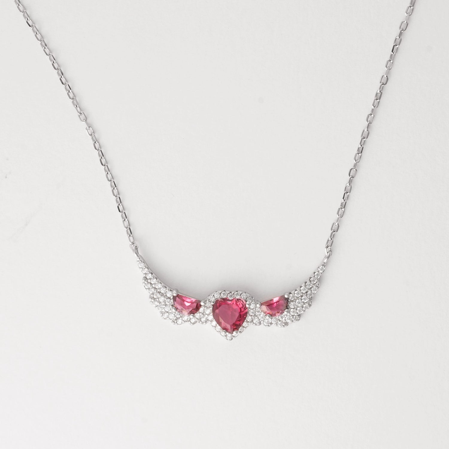 A symbol of love and elegance, the Triple Red Heart Wing Necklace features three dazzling pink heart crystals embraced by wing-like curves of shimmering zircon stones. Set in pure silver, its winged design brings a graceful lift to any look. A perfect blend of charm and sparkle made to brighten your neckline with every wear.