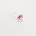 The Ruby Drop ring features a real ruby gemstone in a soft oval cut, set on a sleek silver band with sparkling crystal details.