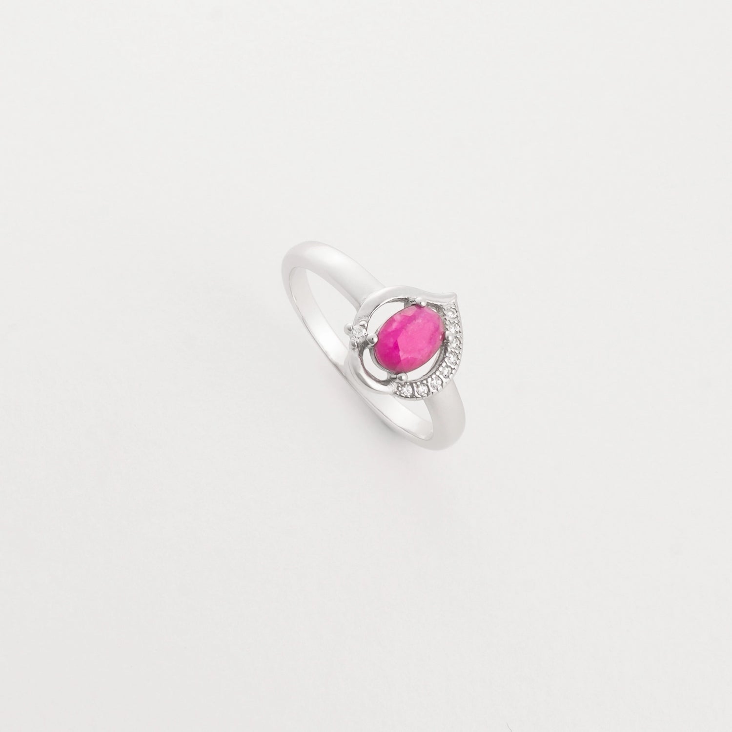 The Ruby Drop ring features a real ruby gemstone in a soft oval cut, set on a sleek silver band with sparkling crystal details.