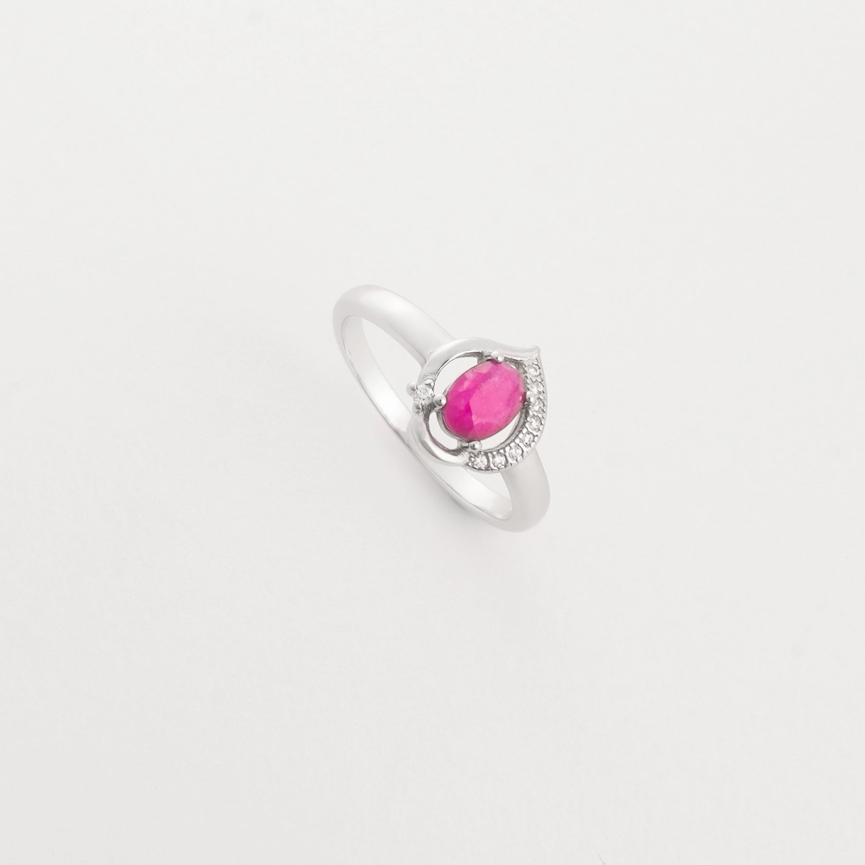 The Ruby Drop ring features a real ruby gemstone in a soft oval cut, set on a sleek silver band with sparkling crystal details.